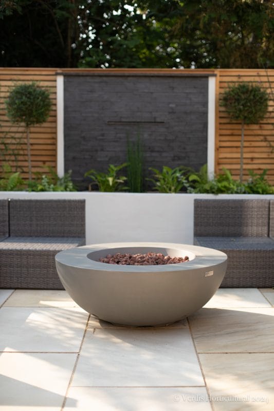 Garden patio fire pit outdoor seating fence topiary plants flower beds raised beds sandstone patio wicker contemporary light open
